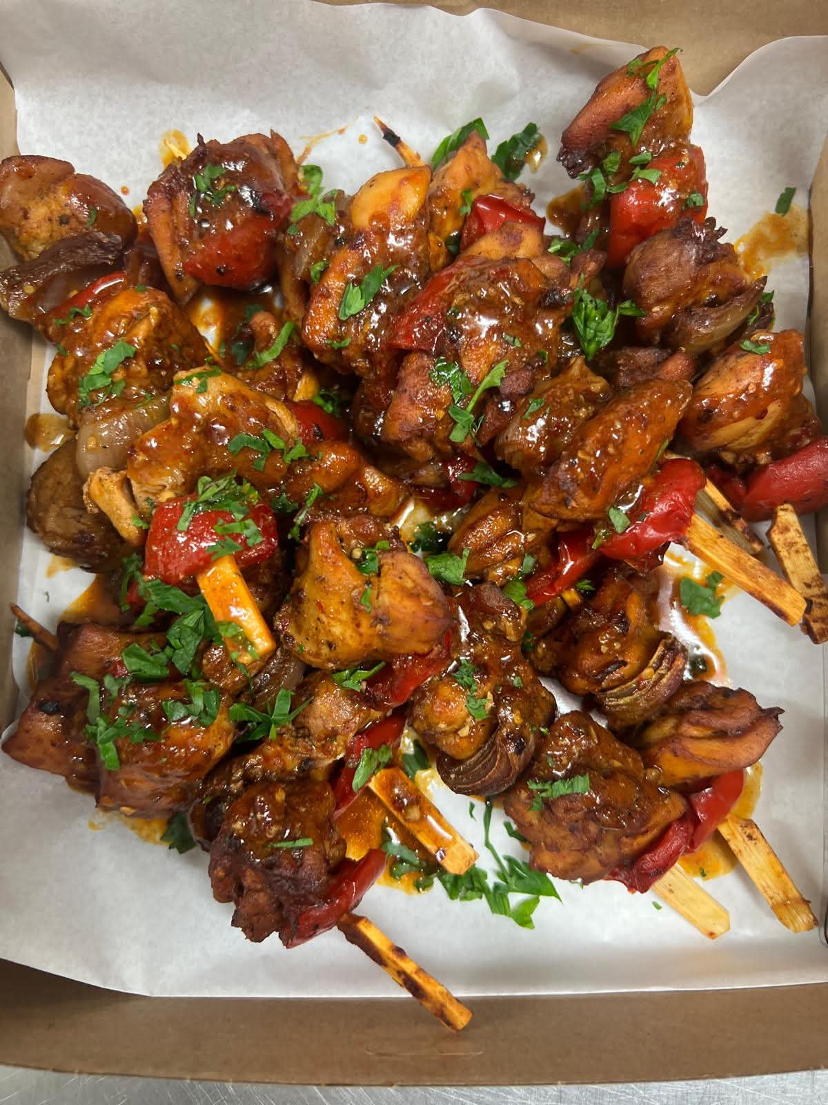 Marinated chicken and capsicum skewers glazed and topped with fresh parsley.