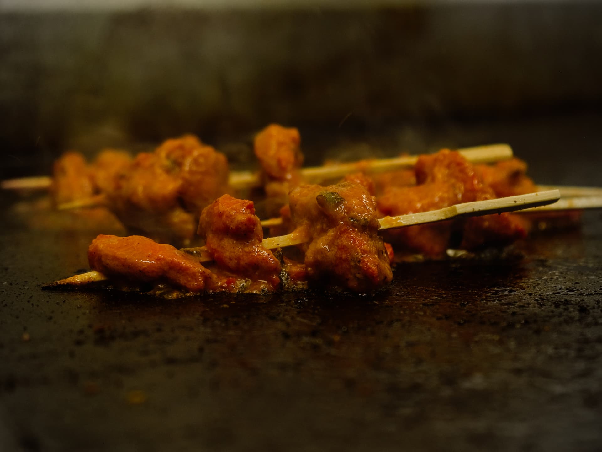 Marinated chicken skewers cooking on the grill plate.